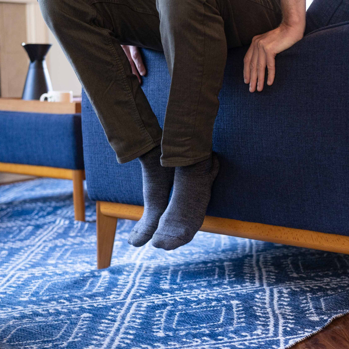 Person sitting on a blue couch with feet up on a matching blue rug.