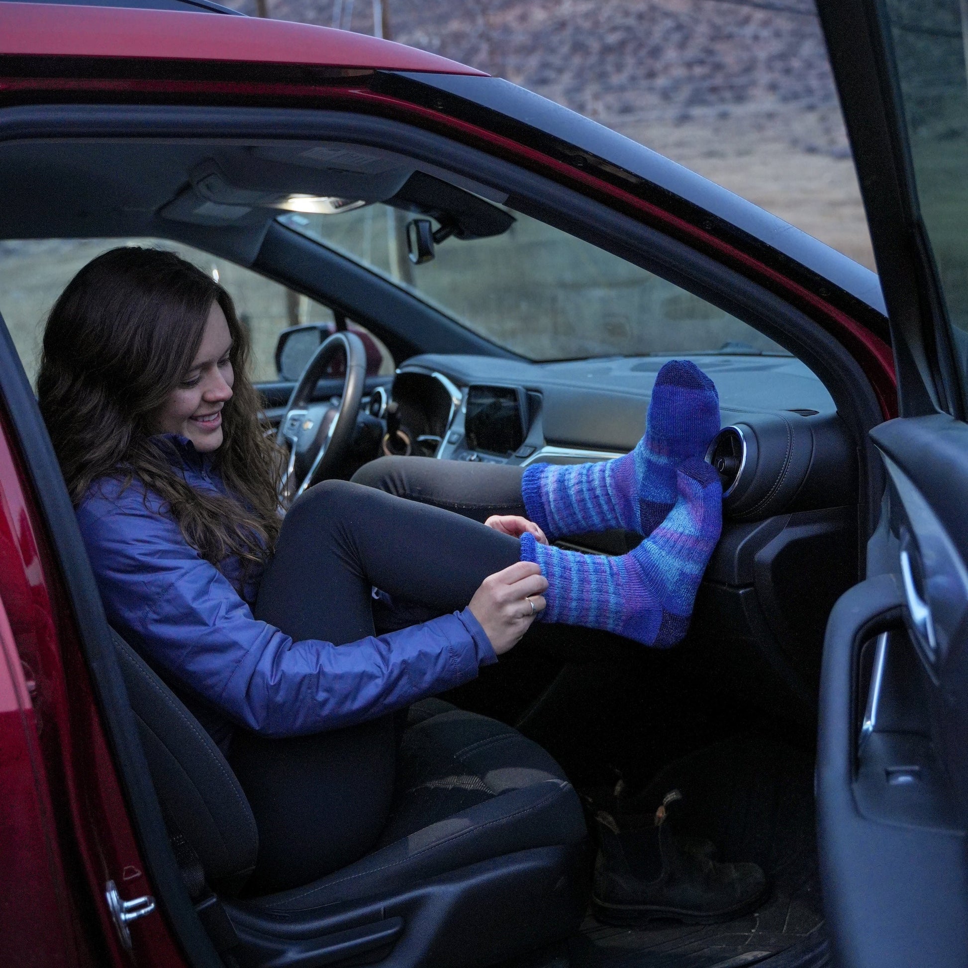 Person sitting in a car with mountains in the background